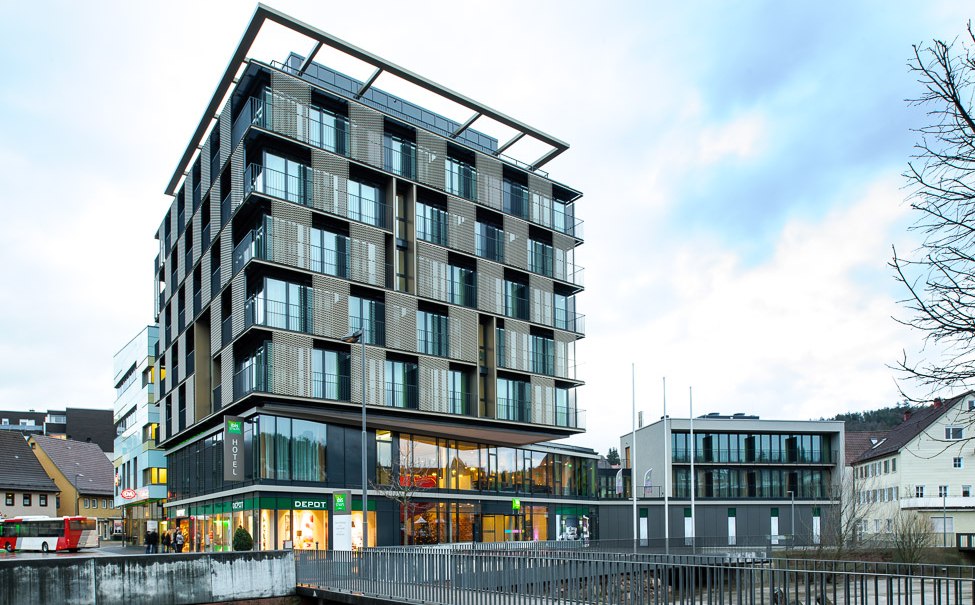 Ein modernes Gebäude mit Glasfassade und Geschäften im Erdgeschoss. Es hat mehrere Stockwerke und eine markante Architektur., © TOMAS Ein modernes Gebäude mit Glasfassade und Geschäften im Erdgeschoss. Es hat mehrere Stockwerke und eine markante Architektur., © TOMAS