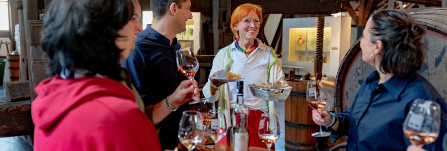 Eine Gruppe von Menschen genie&szlig;t eine Weinprobe im Weinbaumuseum. Eine Frau serviert Snacks, w&auml;hrend die anderen Wein in Gl&auml;sern halten., &copy; Stuttgart-Marketing GmbH, Thomas Niederm&uuml;ller