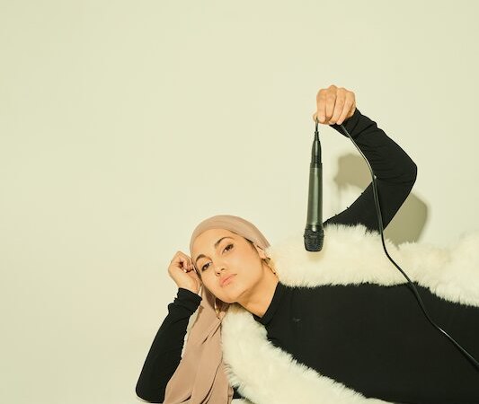 Person liegt auf dem Boden, hält ein Mikrofon in der Hand, trägt einen hellen Schal und schwarze Kleidung., © Rosenau Kultur e.V. Person liegt auf dem Boden, hält ein Mikrofon in der Hand, trägt einen hellen Schal und schwarze Kleidung., © Rosenau Kultur e.V.