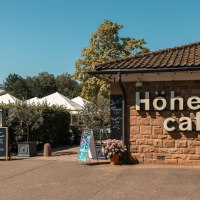 The Höhen Café with signs and plants outside in sunny weather., © SMG Stuttgart Marketing GmbH - Sarah Schmid