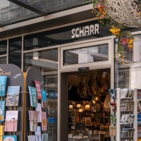 Entrance to the Scharr bookshop with card stands full of greeting cards and hanging flower arrangements. Inside, books and lamps are visible., © SMG Stuttgart Marketing GmbH - Sarah Schmid