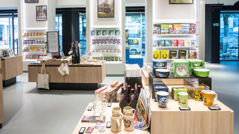 Moderner Souvenirladen mit Holzregalen, gefüllt mit Büchern, Tassen und regionalen Produkten. Große Fenster bieten Blick nach draußen., © Stuttgart-Marketing GmbH, Sarah Schmid