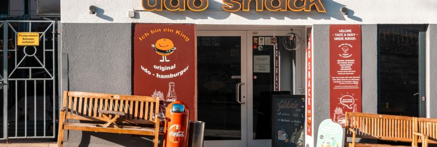 Entrance to the snack bar 'udo snack' with two wooden benches and a garbage can in front of it., © SMG Stuttgart Marketing GmbH - Sarah Schmid Entrance to the snack bar 'udo snack' with two wooden benches and a garbage can in front of it., © SMG Stuttgart Marketing GmbH - Sarah Schmid