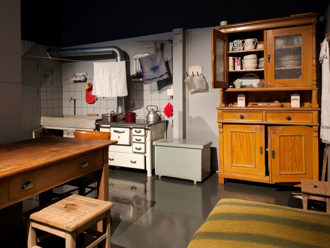 Eine historische Küche mit einem Holzschrank, einem Tisch und einem alten Herd. Geschirr und Küchenutensilien sind sichtbar., © Landesmuseum Württemberg Eine historische Küche mit einem Holzschrank, einem Tisch und einem alten Herd. Geschirr und Küchenutensilien sind sichtbar., © Landesmuseum Württemberg