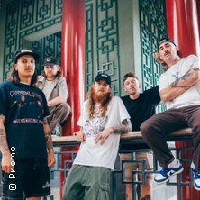 Fünf Personen posieren vor einem Gebäude mit roten Säulen und grünen Mustern. Sie tragen lässige Kleidung und schauen in die Kamera., © links im Bild Fünf Personen posieren vor einem Gebäude mit roten Säulen und grünen Mustern. Sie tragen lässige Kleidung und schauen in die Kamera., © links im Bild