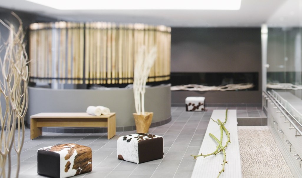 Moderner Wellnessbereich mit Holzbank, gemusterten Hockern und dekorativen Ästen. Entspannte Atmosphäre mit neutralen Farben und stilvollem Design., © Mövenpick Hotel Stuttgart Airport Moderner Wellnessbereich mit Holzbank, gemusterten Hockern und dekorativen Ästen. Entspannte Atmosphäre mit neutralen Farben und stilvollem Design., © Mövenpick Hotel Stuttgart Airport