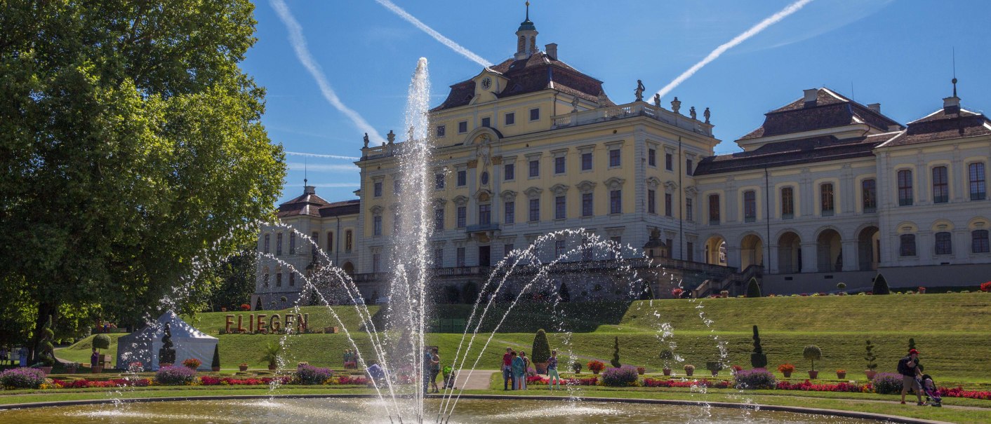 Ludwigsburg Palace with its magnificent garden and fountain, surrounded by blooming flowers. The sky is blue with vapor trails., © Tourismus & Events Ludwigsburg
