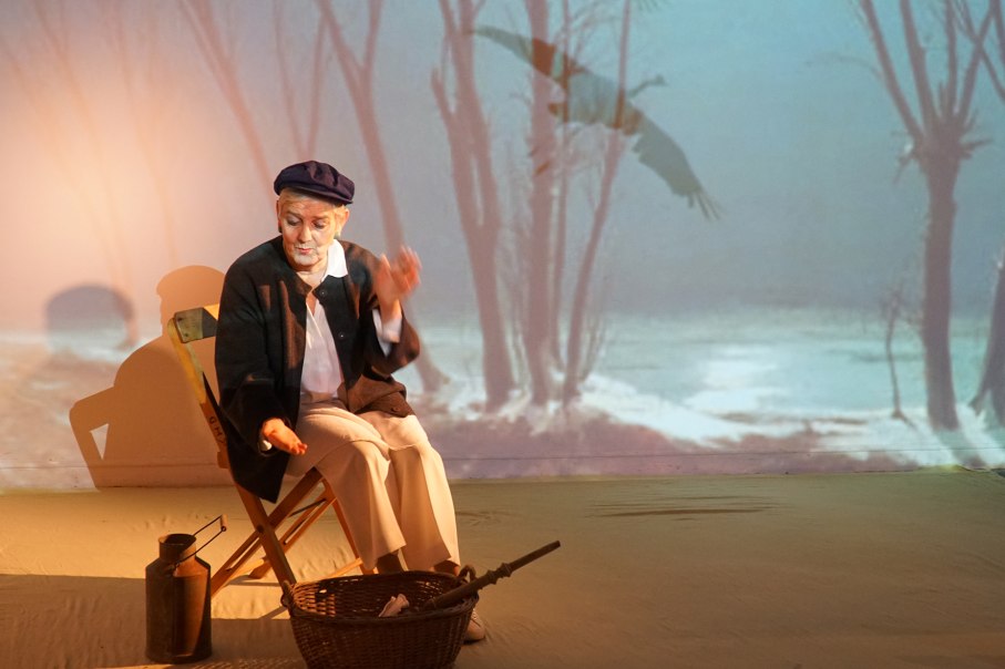 A person sits on a chair in front of a projection of trees and a flying bird. A basket and a jug are on the floor., &copy; Katja Ritter