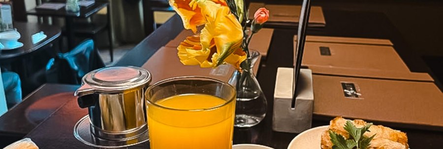 Asian dishes on a table: spring rolls, dumplings, rice, vegetables and a glass of orange juice. A cozy restaurant ambience in the background., © by Canto