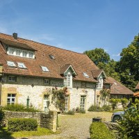A charming, historic building with a red-tiled roof and blooming roses along the facade, surrounded by lush greenery and a paved path., &copy; SMG Stuttgart Marketing GmbH - Sarah Schmid