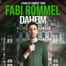 Ein Mann hält ein Mikrofon vor einem Fachwerkhaus. Text: Fabi Rommel - Daheim, Stand Up Comedy Tour., © links im Bild