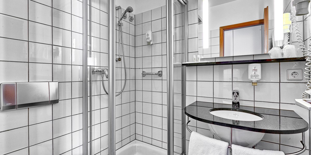Modernes Badezimmer mit gefliester Dusche, Waschbecken, Spiegel und Handtuchhalter. Helle Beleuchtung und saubere, weiße Fliesen., © attimo Modernes Badezimmer mit gefliester Dusche, Waschbecken, Spiegel und Handtuchhalter. Helle Beleuchtung und saubere, weiße Fliesen., © attimo
