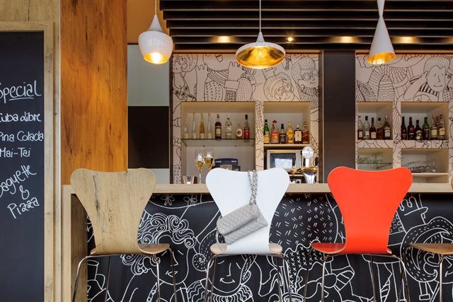 Bar mit bunten St&uuml;hlen, dekorativer Wand und Tafel mit Getr&auml;nkespezialit&auml;ten. Moderne Lampen und Flaschen im Hintergrund., &copy; TOMAS