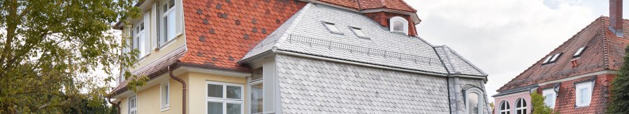 Two-storey house with red tiled roof, yellow fa&ccedil;ade and white windows, surrounded by trees and lawn., &copy; Philip Kottlorz