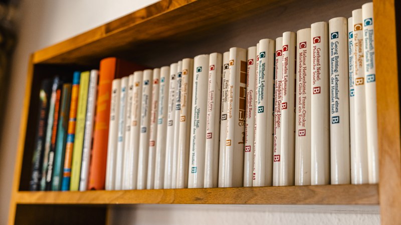 A wooden shelf with a row of books in white bindings, neatly lined up next to each other., © SMG Stuttgart Marketing GmbH - Sarah Schmid A wooden shelf with a row of books in white bindings, neatly lined up next to each other., © SMG Stuttgart Marketing GmbH - Sarah Schmid