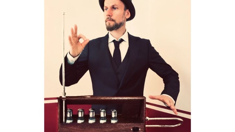Ein Mann im Anzug und Hut spielt ein Theremin, ein elektronisches Musikinstrument, mit Gesten der Hände in der Luft., © Fotocredit Theater La Lune Stuttgart Ein Mann im Anzug und Hut spielt ein Theremin, ein elektronisches Musikinstrument, mit Gesten der Hände in der Luft., © Fotocredit Theater La Lune Stuttgart