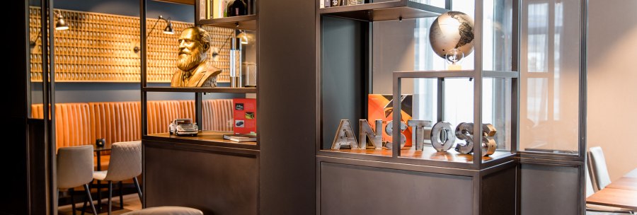 Modernes Café mit Regalen, Büchern, einer Büste und einem Globus. Sitzbereich mit braunen Polstern und stilvollen Stühlen., © TOMAS Modernes Café mit Regalen, Büchern, einer Büste und einem Globus. Sitzbereich mit braunen Polstern und stilvollen Stühlen., © TOMAS