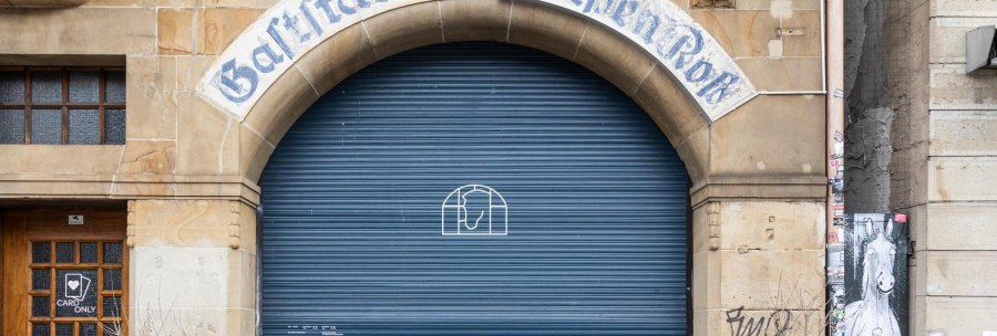 Eingang mit der Aufschrift 'Gastst&auml;tte zum wei&szlig;en Ro&szlig;' &uuml;ber einem blauen Rolltor. Daneben eine Holzt&uuml;r mit 'Card Only'-Schild., &copy; Stuttgart-Marketing GmbH, Sarah Schmid