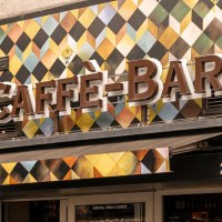 Fassade einer Caffè-Bar mit buntem Rautenmuster und einem Birra Moretti Schild an der Wand., © Stuttgart-Marketing GmbH, Sarah Schmid Fassade einer Caffè-Bar mit buntem Rautenmuster und einem Birra Moretti Schild an der Wand., © Stuttgart-Marketing GmbH, Sarah Schmid
