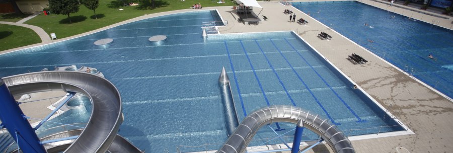 Freibad Rosental mit großer Wasserrutsche, mehreren Schwimmbecken und umliegenden Grünflächen. Menschen entspannen auf der Wiese., © Stuttgarter Bäder Freibad Rosental mit großer Wasserrutsche, mehreren Schwimmbecken und umliegenden Grünflächen. Menschen entspannen auf der Wiese., © Stuttgarter Bäder
