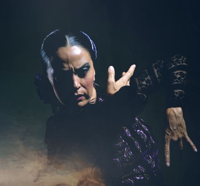 Flamenco-Tänzerin in intensiver Pose, gekleidet in schwarzer Spitze, mit ausdrucksstarker Gestik vor dunklem Hintergrund., © Theaterhaus Stuttgart e.V. Flamenco-Tänzerin in intensiver Pose, gekleidet in schwarzer Spitze, mit ausdrucksstarker Gestik vor dunklem Hintergrund., © Theaterhaus Stuttgart e.V.