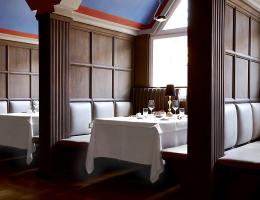 Elegant restaurant with wooden walls, laid tables and cozy benches. Warm lighting and stylish decoration create an inviting atmosphere., &copy; Waldhotel Stuttgart GmbH
