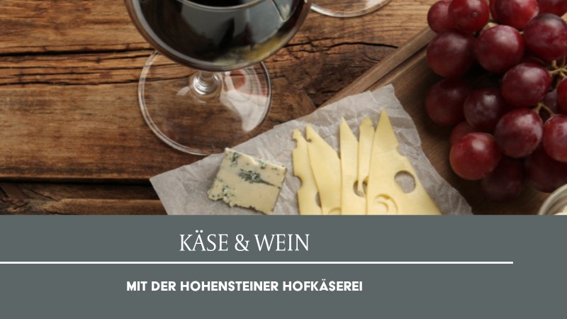 A glass of red wine, slices of cheese, blue cheese, and red grapes on a wooden table. Text: Cheese & Wine with the Hohensteiner Hofkäserei., © Weinmanufaktur Stuttgart eG A glass of red wine, slices of cheese, blue cheese, and red grapes on a wooden table. Text: Cheese & Wine with the Hohensteiner Hofkäserei., © Weinmanufaktur Stuttgart eG