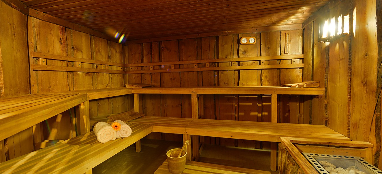 Wooden sauna with benches, towels and sauna heater. Cozy lighting and rustic ambience., © Amber Hotel Leonberg / Stuttgart Wooden sauna with benches, towels and sauna heater. Cozy lighting and rustic ambience., © Amber Hotel Leonberg / Stuttgart