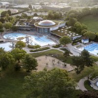 Luftaufnahme des Wunnebads in Winnenden: Schwimmbecken, Rutschen und grüne Umgebung. Sportplatz im Hintergrund., © Stadtwerke Winnenden GmbH