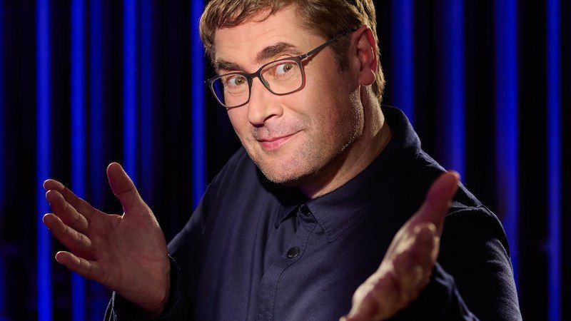 Ein Mann mit Brille und dunklem Hemd gestikuliert vor einem blauen Hintergrund. Er wirkt freundlich und selbstbewusst., © Renitenztheater Stuttgart e.V. Ein Mann mit Brille und dunklem Hemd gestikuliert vor einem blauen Hintergrund. Er wirkt freundlich und selbstbewusst., © Renitenztheater Stuttgart e.V.