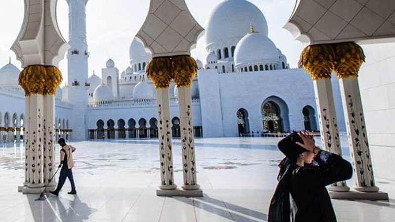 Innenhof der Sheikh Zayed Moschee mit kunstvollen Säulen. Eine Person in traditioneller Kleidung und eine weitere Person sind zu sehen., © Theaterhaus Stuttgart e.V.
