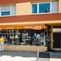 Ein Mann betrachtet das Schaufenster des Geschäfts 'Seifen Lenz', das seit 1785 besteht. Das Gebäude hat eine orangefarbene Markise., © SMG Stuttgart Marketing GmbH - Sarah Schmid