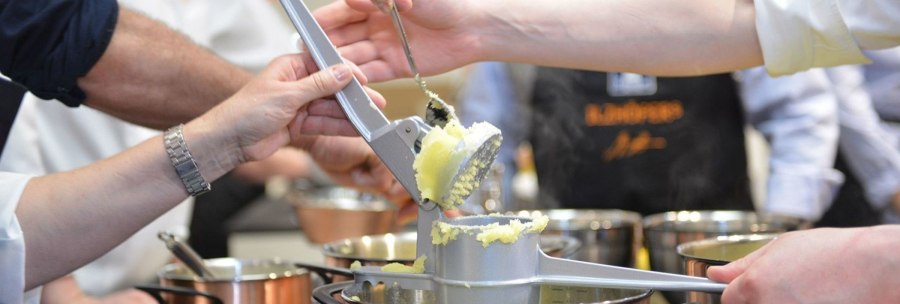 Several people use a potato ricer to press potatoes into a pot. More pots can be seen in the background., © Ilzhöfer, Stuttgart Several people use a potato ricer to press potatoes into a pot. More pots can be seen in the background., © Ilzhöfer, Stuttgart