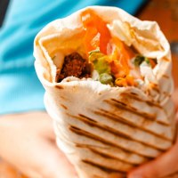 Ein gefüllter Wrap mit Gemüse und Falafel wird von einer Person in blauer Kleidung gehalten., © Stuttgart-Marketing GmbH, Sarah Schmid Ein gefüllter Wrap mit Gemüse und Falafel wird von einer Person in blauer Kleidung gehalten., © Stuttgart-Marketing GmbH, Sarah Schmid