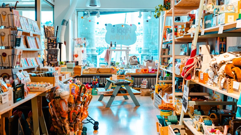 Bunter Spielzeugladen mit Regalen voller Spielsachen, Büchern und Accessoires. Ein Tisch steht in der Mitte, das Schild "Pippi & Annika" im Hintergrund., © SMG_Sarah Schmid Bunter Spielzeugladen mit Regalen voller Spielsachen, Büchern und Accessoires. Ein Tisch steht in der Mitte, das Schild "Pippi & Annika" im Hintergrund., © SMG_Sarah Schmid