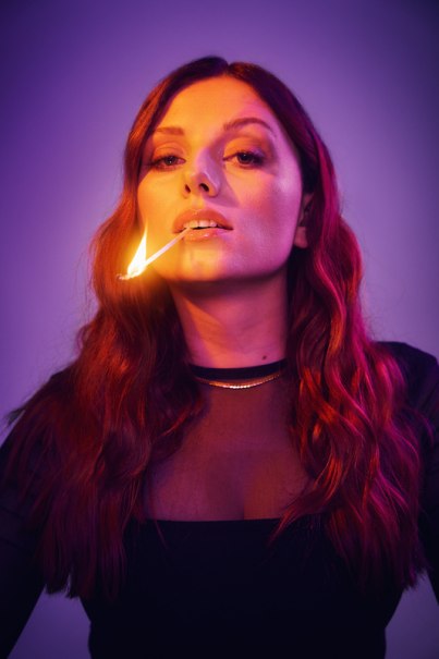 Frau mit langen, welligen Haaren h&auml;lt ein brennendes Streichholz im Mund. Sie tr&auml;gt ein schwarzes Oberteil und ist in violettes Licht getaucht., &copy; Rosenau Kultur e.V.