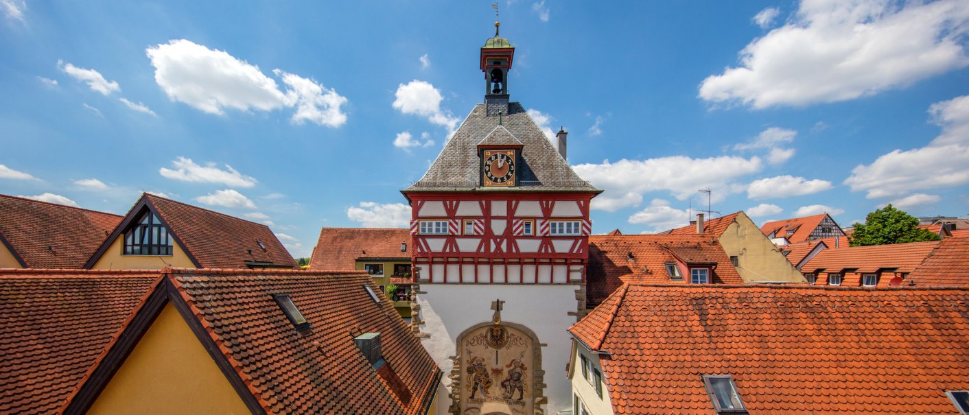 A half-timbered building with a clock tower in Bietigheim-Bissingen, surrounded by red-tiled roofs and a blue sky., © © Stuttgart-Marketing GmbH A half-timbered building with a clock tower in Bietigheim-Bissingen, surrounded by red-tiled roofs and a blue sky., © © Stuttgart-Marketing GmbH