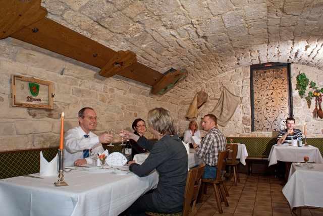 Ein rustikales Gewölberestaurant mit Steinwänden. Gäste sitzen an Tischen, genießen Essen und Getränke. Eine gemütliche Atmosphäre mit Kerzenlicht., © Ulli Kellenbenz