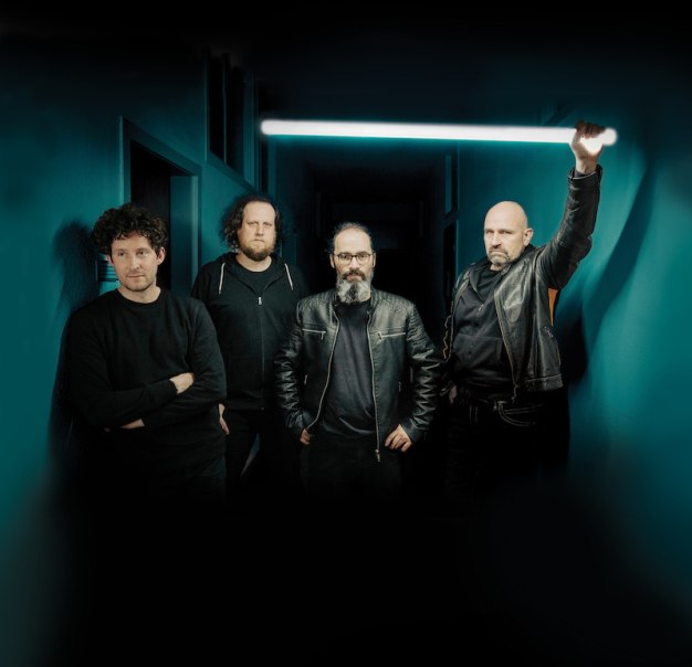 Vier Männer in dunkler Kleidung stehen in einem Flur, einer hält eine leuchtende Röhre hoch., © Rosenau Kultur e.V.