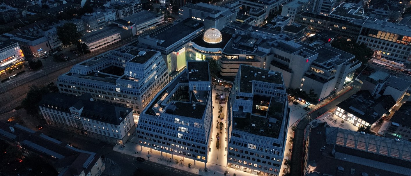 Luftaufnahme des Dorotheen Quartiers in Stuttgart bei Nacht. Moderne Gebäude sind beleuchtet, umgeben von Straßen und anderen Gebäuden., © © Dorotheen Quartier