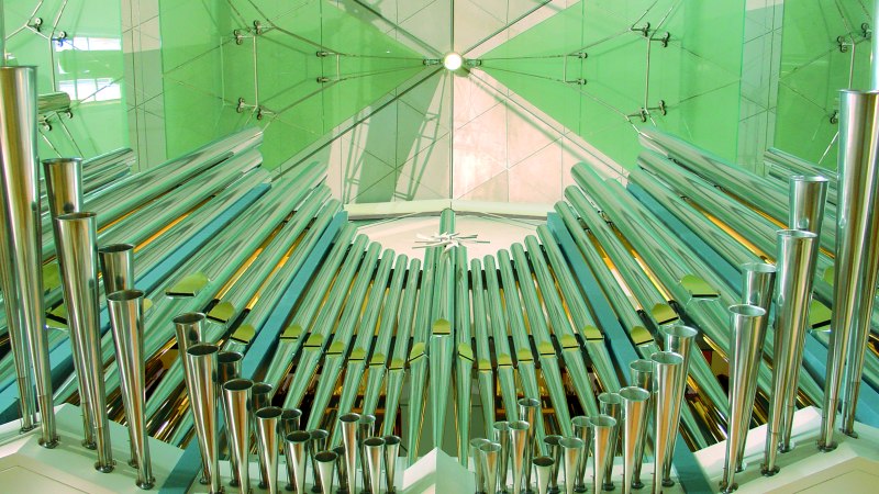 Moderne Orgel mit gl&auml;nzenden Metallpfeifen und gr&uuml;nen Glasplatten im Hintergrund. Die Architektur wirkt futuristisch und elegant., &copy; Stiftsmusik Stuttgart