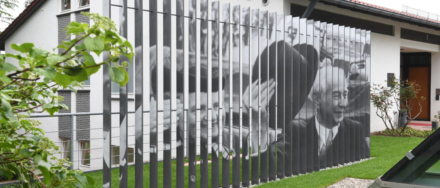 Das Theodor-Heuss-Haus in Stuttgart zeigt eine Fotoinstallation mit schwarz-weißen Bildern auf vertikalen Streben. Im Vordergrund sind Pflanzen zu sehen., © Stiftung Bundespräsident Theodor-Heuss-Haus / Franziska Kraufmann