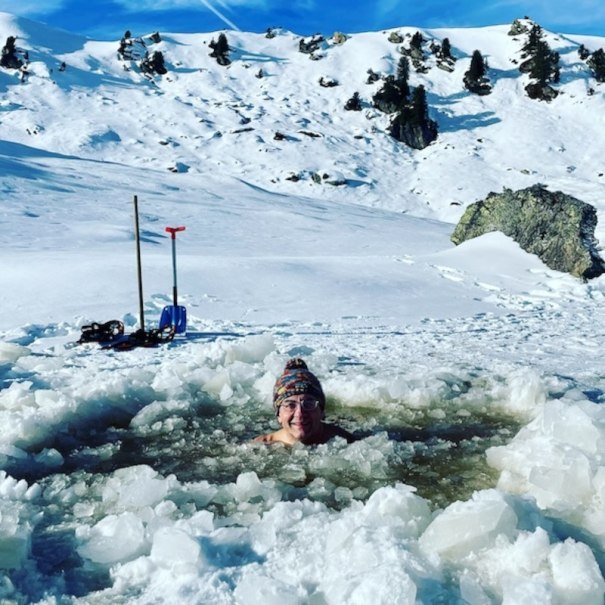 Eine Person badet in einem Eisloch in einer verschneiten Berglandschaft. Im Hintergrund sind Berge und Bäume zu sehen., © Renitenztheater Stuttgart e.V.
