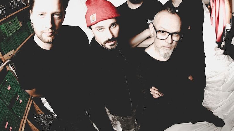 F&uuml;nf M&auml;nner stehen in einem Raum mit wei&szlig;en Vorh&auml;ngen. Einer tr&auml;gt eine rote M&uuml;tze. Die Gruppe wirkt l&auml;ssig und selbstbewusst., &copy; Theaterhaus Stuttgart e.V.