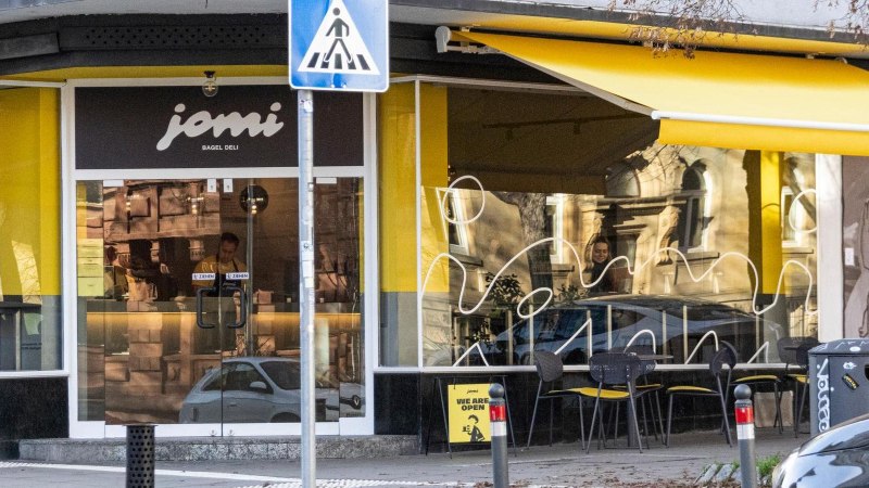 Shop window of the deli with yellow awnings. Above the door at the corner of the building it says "jomi Bagel Deli"., &copy; Stuttgart-Marketing GmbH, Sarah Schmid