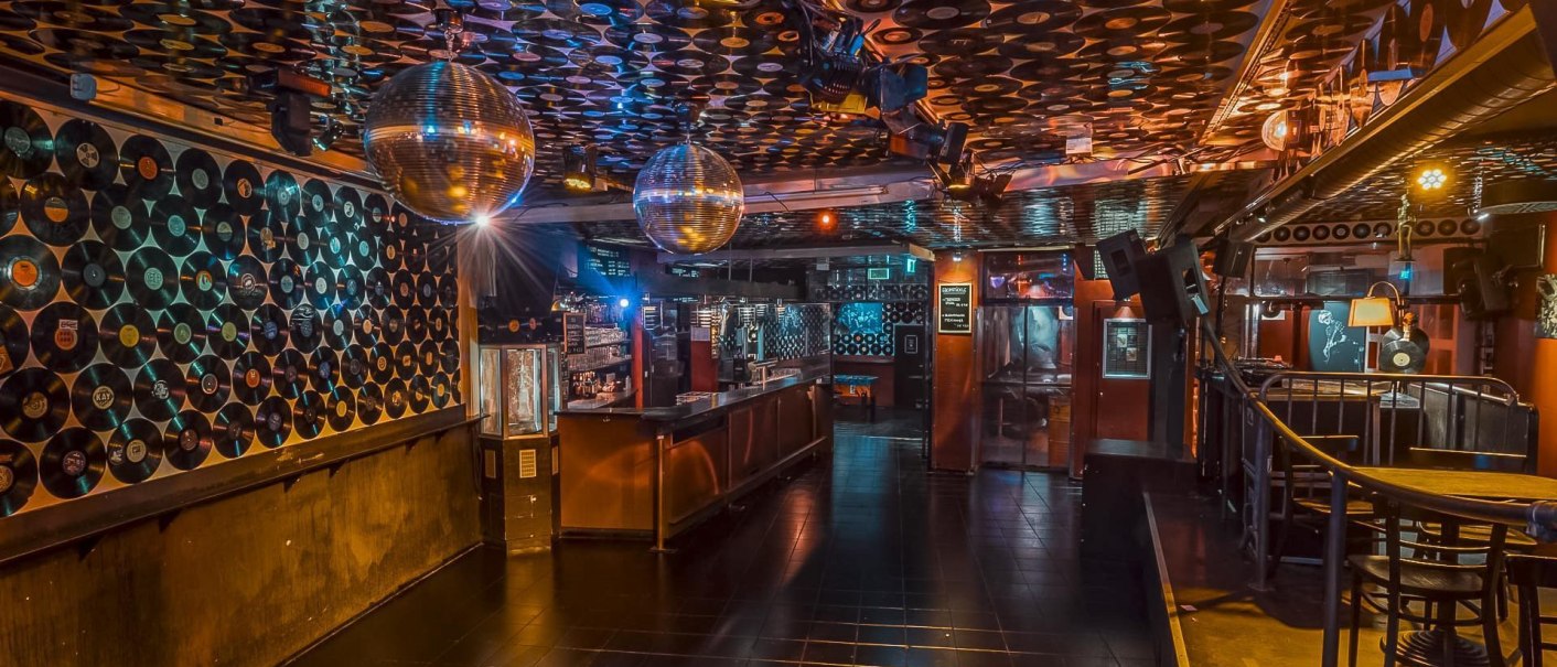 Club with vinyl records on the walls and ceiling, disco balls and bar. Atmospheric lighting and empty dance floor., © Goldmarks, Stuttgart Club with vinyl records on the walls and ceiling, disco balls and bar. Atmospheric lighting and empty dance floor., © Goldmarks, Stuttgart
