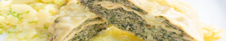 Close-up of Maultaschen with a filling of meat and herbs, served with potato salad on a white plate., © Herr Kächele - Schwäbisches für Schleckige GmbH