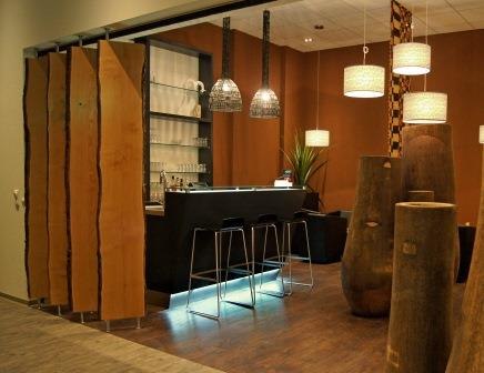 Moderne Bar mit Holzdekor, schwarzen Hockern und stilvollen Lampen. Die Einrichtung wirkt warm und einladend., © TOMAS