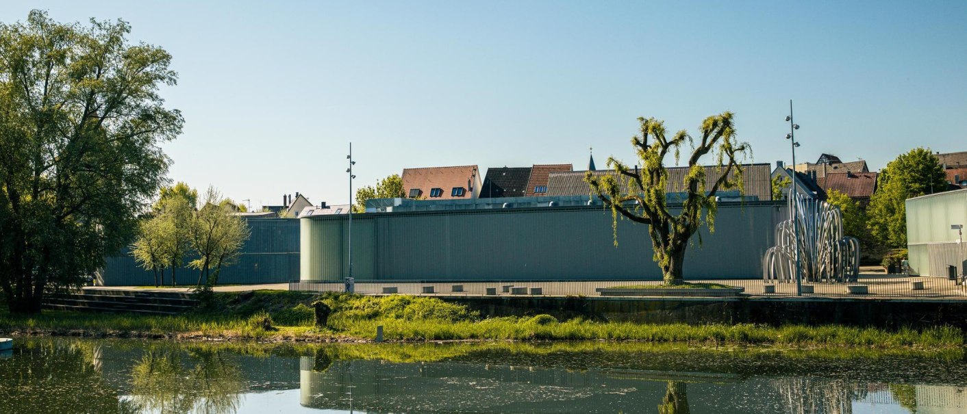 The Stihl Gallery in Waiblingen features modern architecture with a work of art in the foreground. Trees and a calm river complete the scene., © Stuttgart-Marketing GmbH, Sarah Schmid
