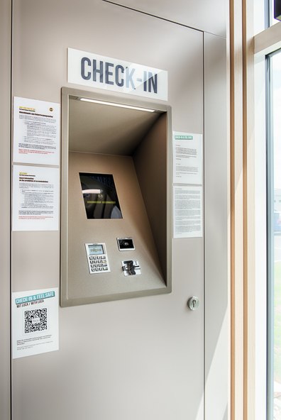 Ein moderner Check-in-Kiosk mit Bildschirm und Tastatur, umgeben von Informationsbl&auml;ttern und einem QR-Code, in einem hellen Raum., &copy; B&B Hotel Stuttgart-Neckarhafen